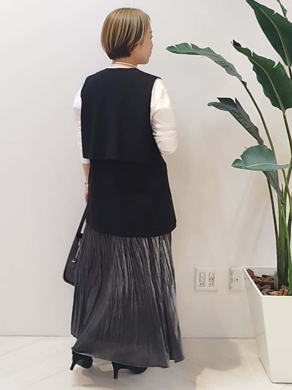 ブラック系のベスト、ホワイト系のTシャツ/カットソー、グレー系のスカートを着用したレディースの冬コーディネートの7枚目の写真