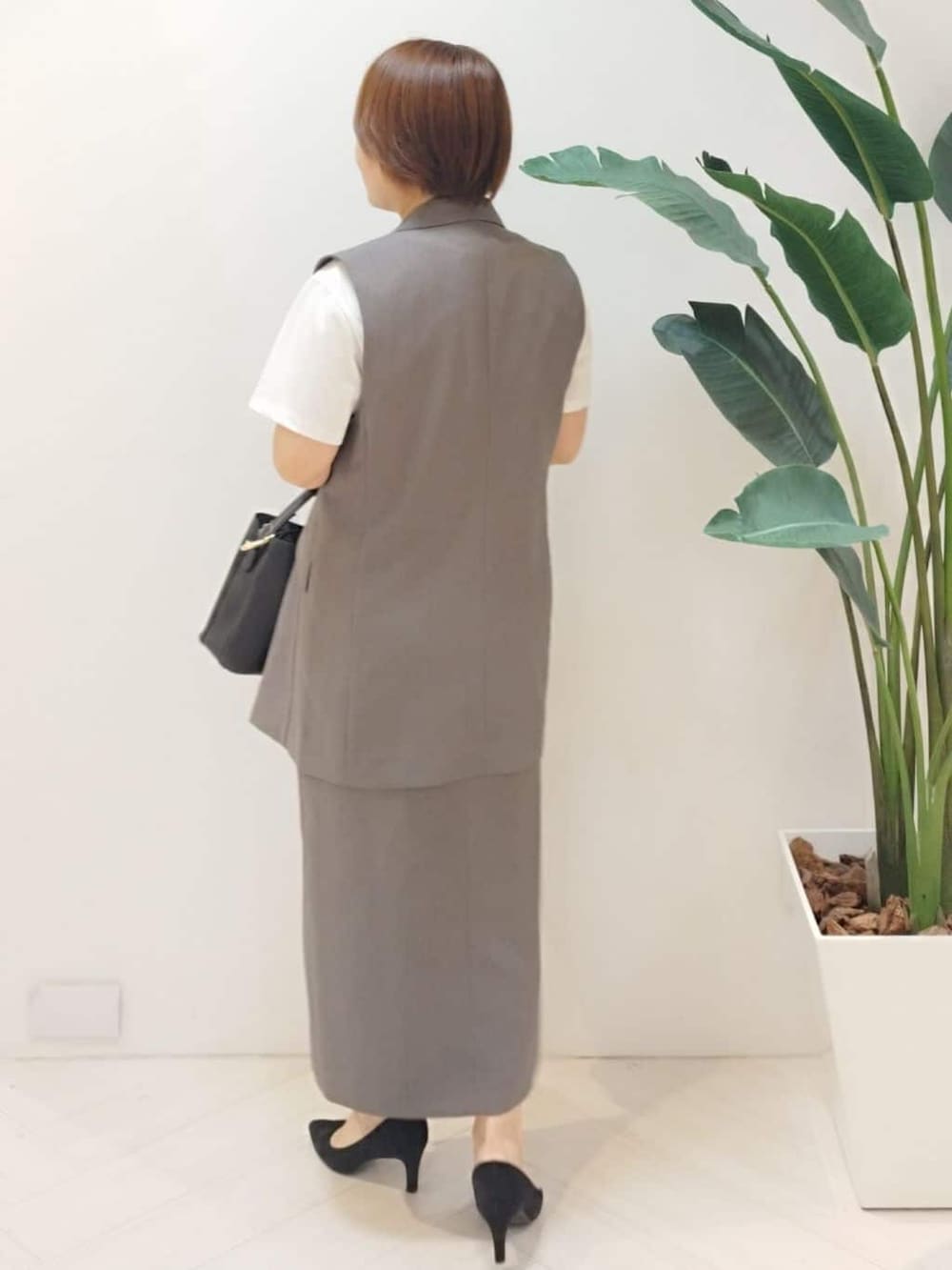 ブラウン系のベスト、ホワイト系のTシャツ/カットソー、ブラウン系のスカートを着用したレディースの秋コーディネートの6枚目の写真