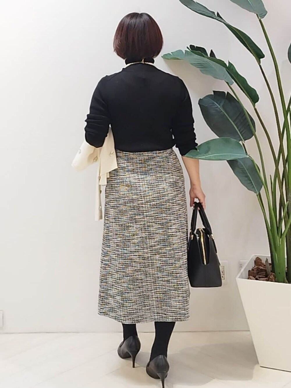ブラック系のニット/セーター、ブラック系のスカート、ホワイト系のカーディガン/ボレロを着用したレディースの秋コーディネートの7枚目の写真