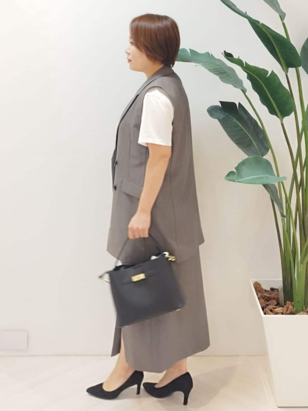 ブラウン系のベスト、ホワイト系のTシャツ/カットソー、ブラウン系のスカートを着用したレディースの秋コーディネートの5枚目の写真