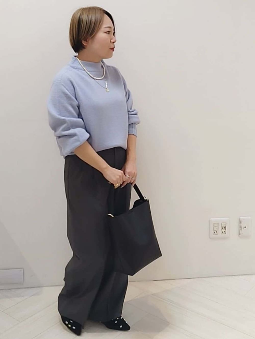 パープル系のニット/セーター、グレー系のその他パンツ、ブラック系のトートバッグを着用したレディースの冬コーディネートの2枚目の写真
