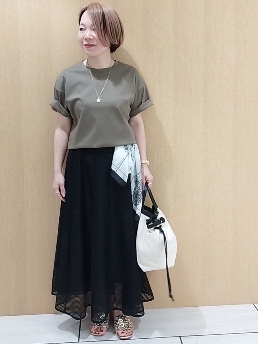 グリーン系のTシャツ/カットソー、ブラック系のスカートを着用したレディースの春コーディネートの6枚目の写真