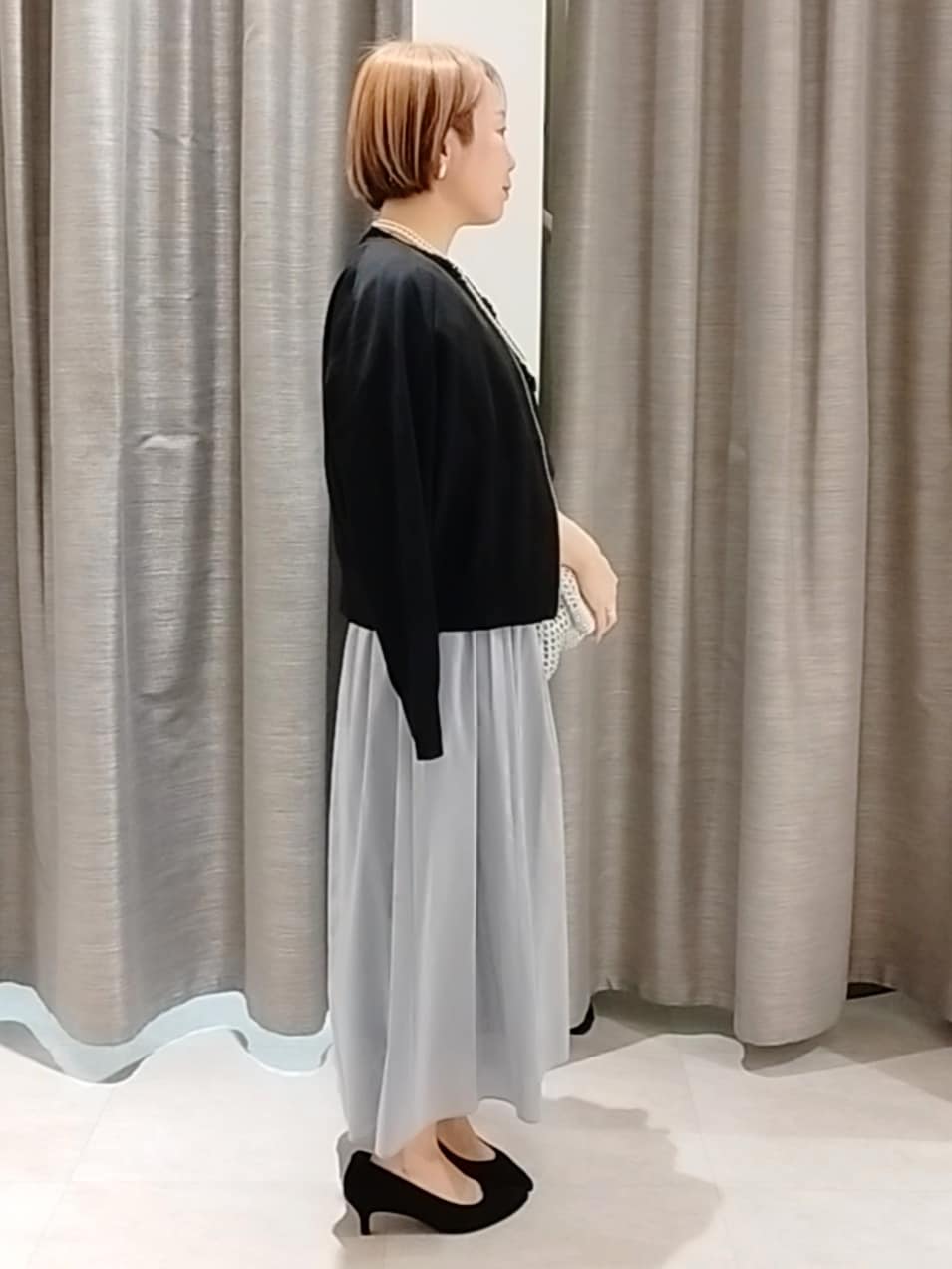 ブルー系のスカート、ブラック系のカーディガン/ボレロ、シルバー系のトートバッグを着用したレディースの春コーディネートの4枚目の写真