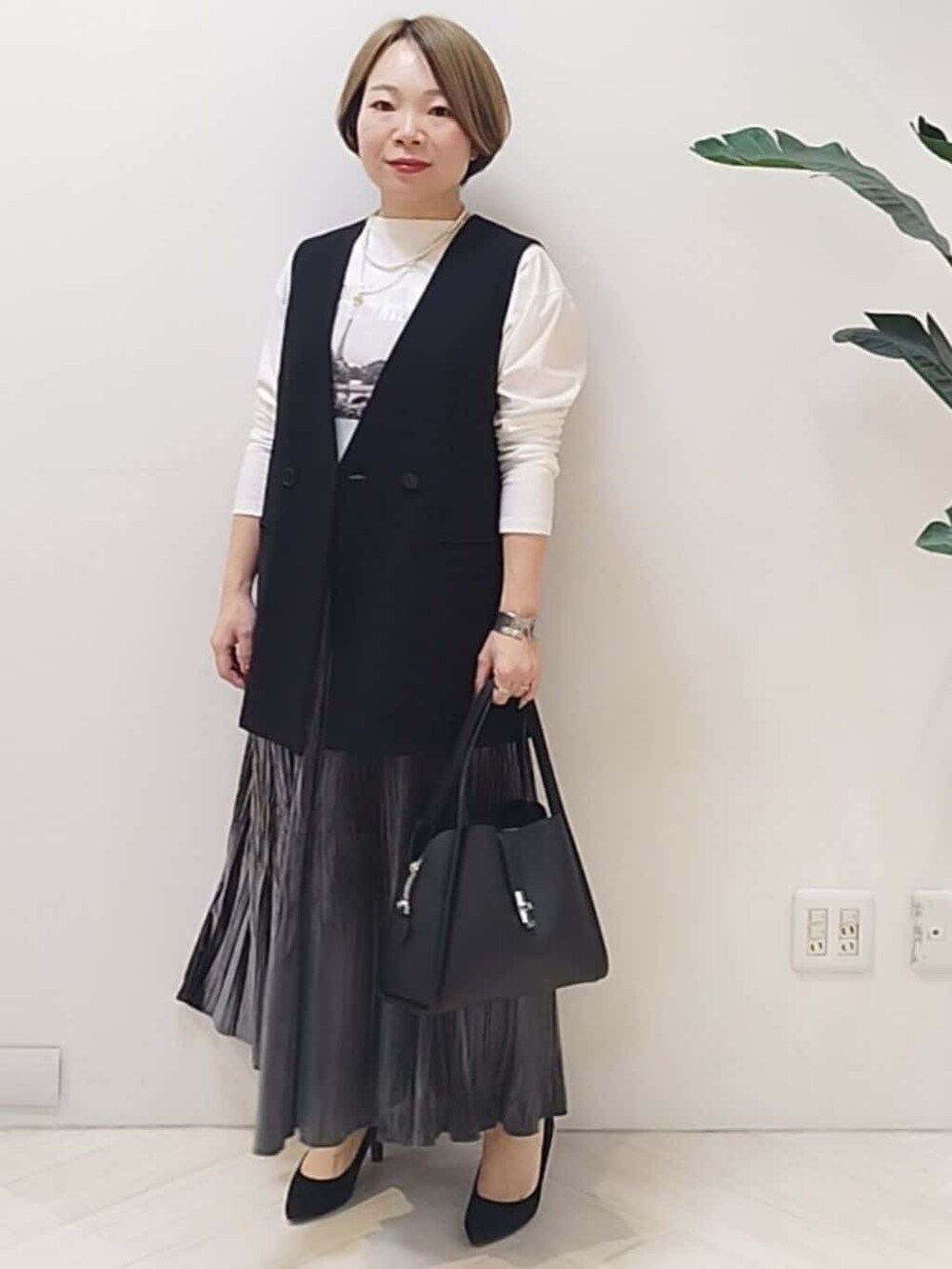 ブラック系のベスト、ホワイト系のTシャツ/カットソー、グレー系のスカートを着用したレディースの冬コーディネートの3枚目の写真