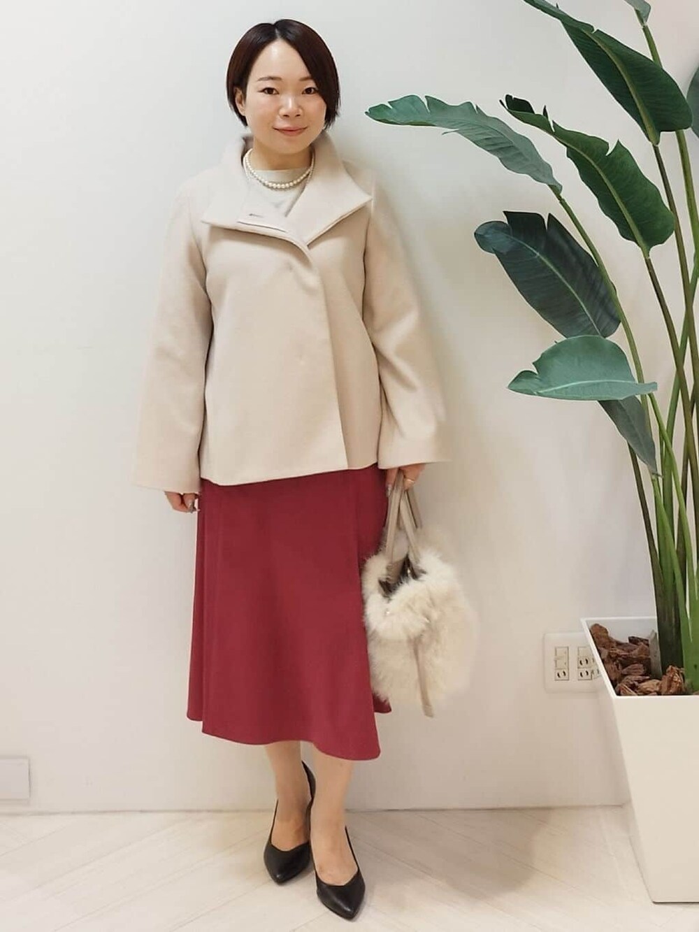 ベージュ系のその他アウター、ベージュ系のニット/セーター、レッド系のスカートを着用したレディースの冬コーディネートの2枚目の写真