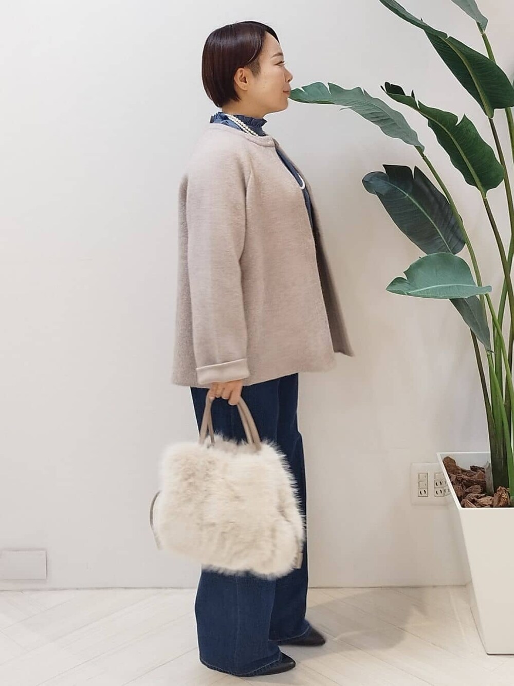 ベージュ系のカーディガン/ボレロ、ブルー系のシャツ/ブラウス、ブルー系のデニムパンツを着用したレディースの冬コーディネートの2枚目の写真