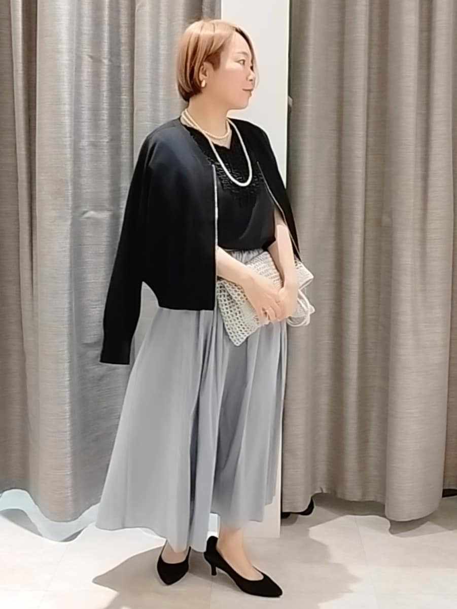 ブルー系のスカート、ブラック系のカーディガン/ボレロ、シルバー系のトートバッグを着用したレディースの春コーディネートの3枚目の写真