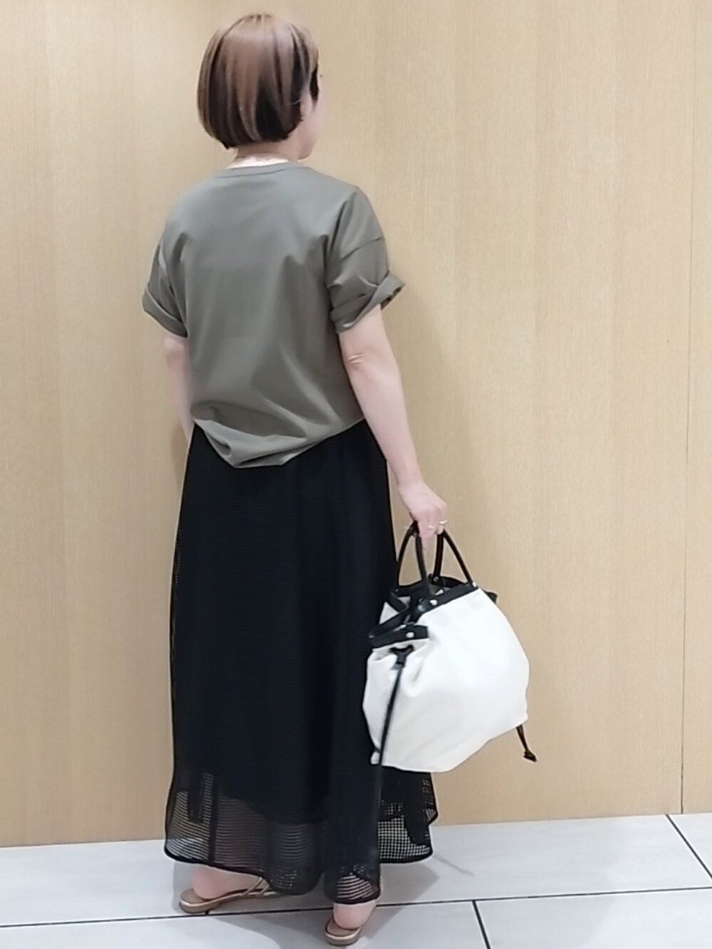グリーン系のTシャツ/カットソー、ブラック系のスカートを着用したレディースの春コーディネートの5枚目の写真