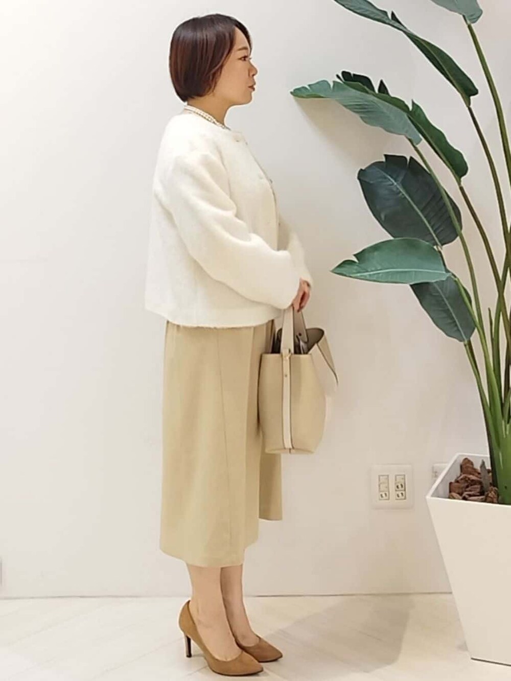 ホワイト系のカーディガン/ボレロ、ベージュ系のワンピース、ベージュ系のショルダーバッグを着用したレディースの秋コーディネートの3枚目の写真