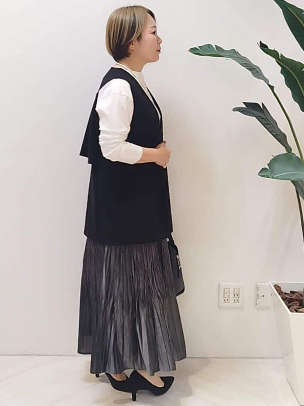 ブラック系のベスト、ホワイト系のTシャツ/カットソー、グレー系のスカートを着用したレディースの冬コーディネートの6枚目の写真