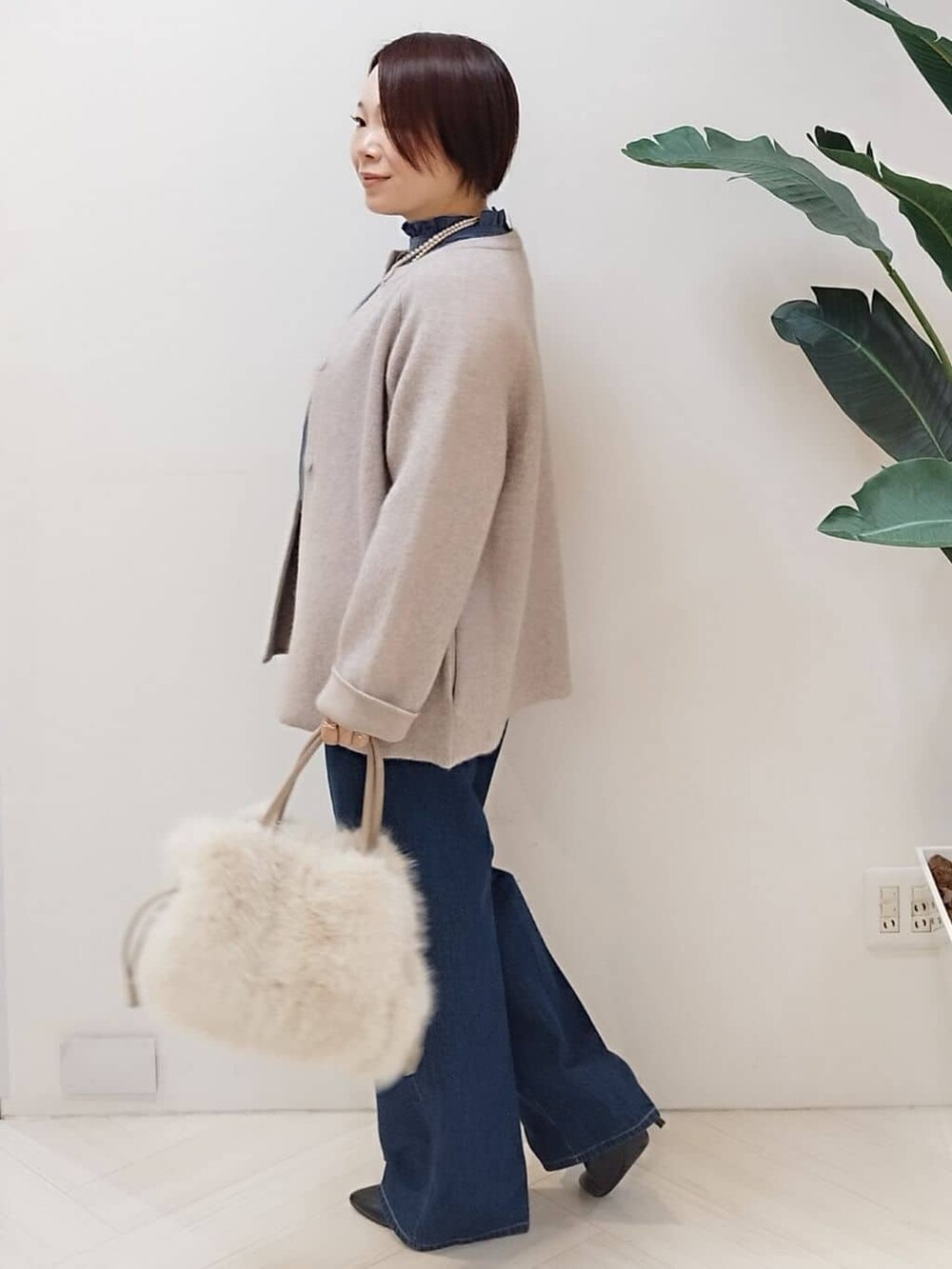 ベージュ系のカーディガン/ボレロ、ブルー系のシャツ/ブラウス、ブルー系のデニムパンツを着用したレディースの冬コーディネートの4枚目の写真