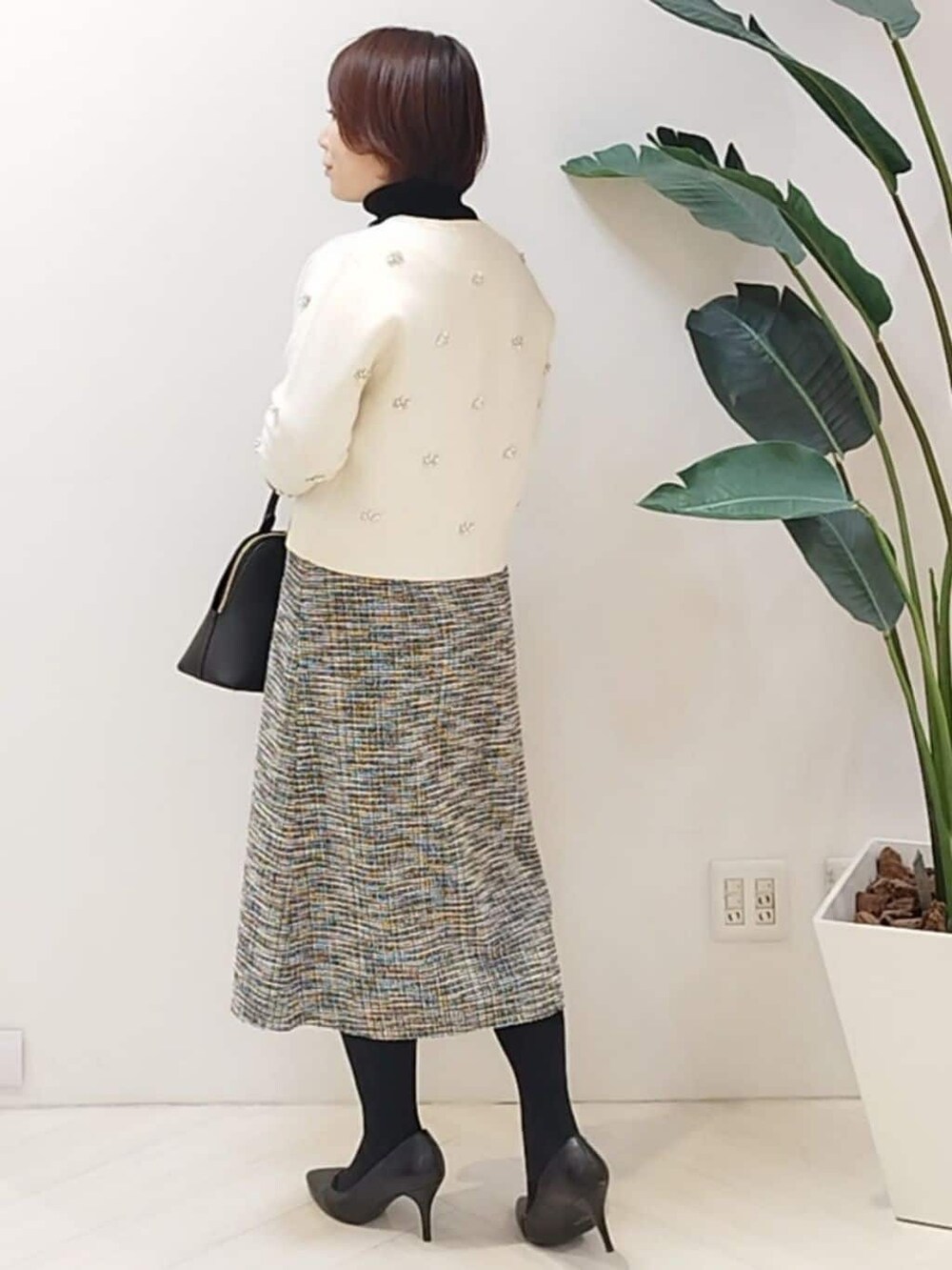 ホワイト系のカーディガン/ボレロ、ブラック系のニット/セーター、ブラック系のスカートを着用したレディースの秋コーディネートの5枚目の写真