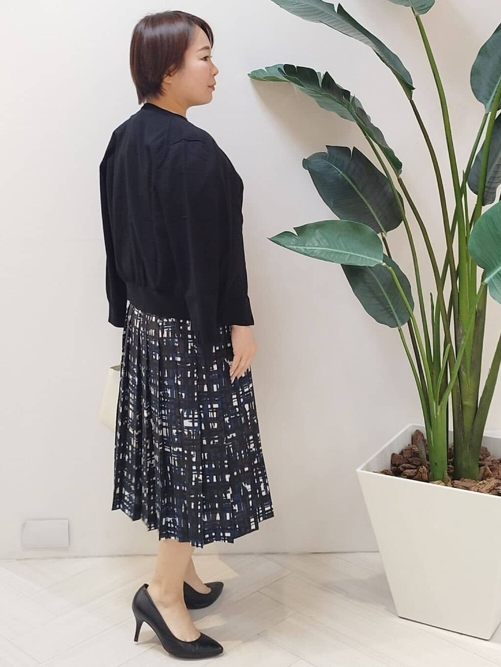 ブラック系のカーディガン/ボレロ、ブラック系のニット/セーター、ブルー系のスカートを着用したレディースの春コーディネートの6枚目の写真