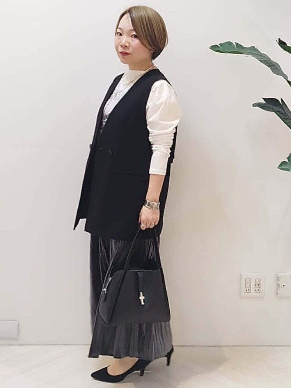 ブラック系のベスト、ホワイト系のTシャツ/カットソー、グレー系のスカートを着用したレディースの冬コーディネートの4枚目の写真