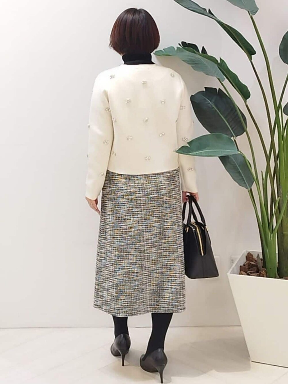 ホワイト系のカーディガン/ボレロ、ブラック系のニット/セーター、ブラック系のスカートを着用したレディースの秋コーディネートの6枚目の写真