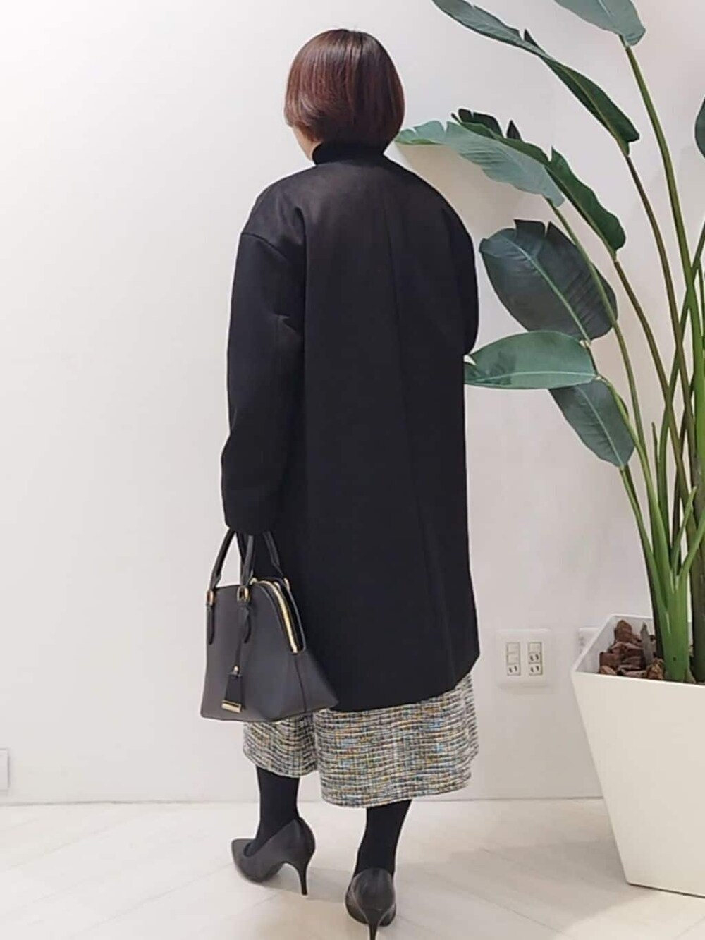 ブラック系のノーカラーコート、ブラック系のTシャツ/カットソー、ブラック系のスカートを着用したレディースの秋コーディネートの6枚目の写真