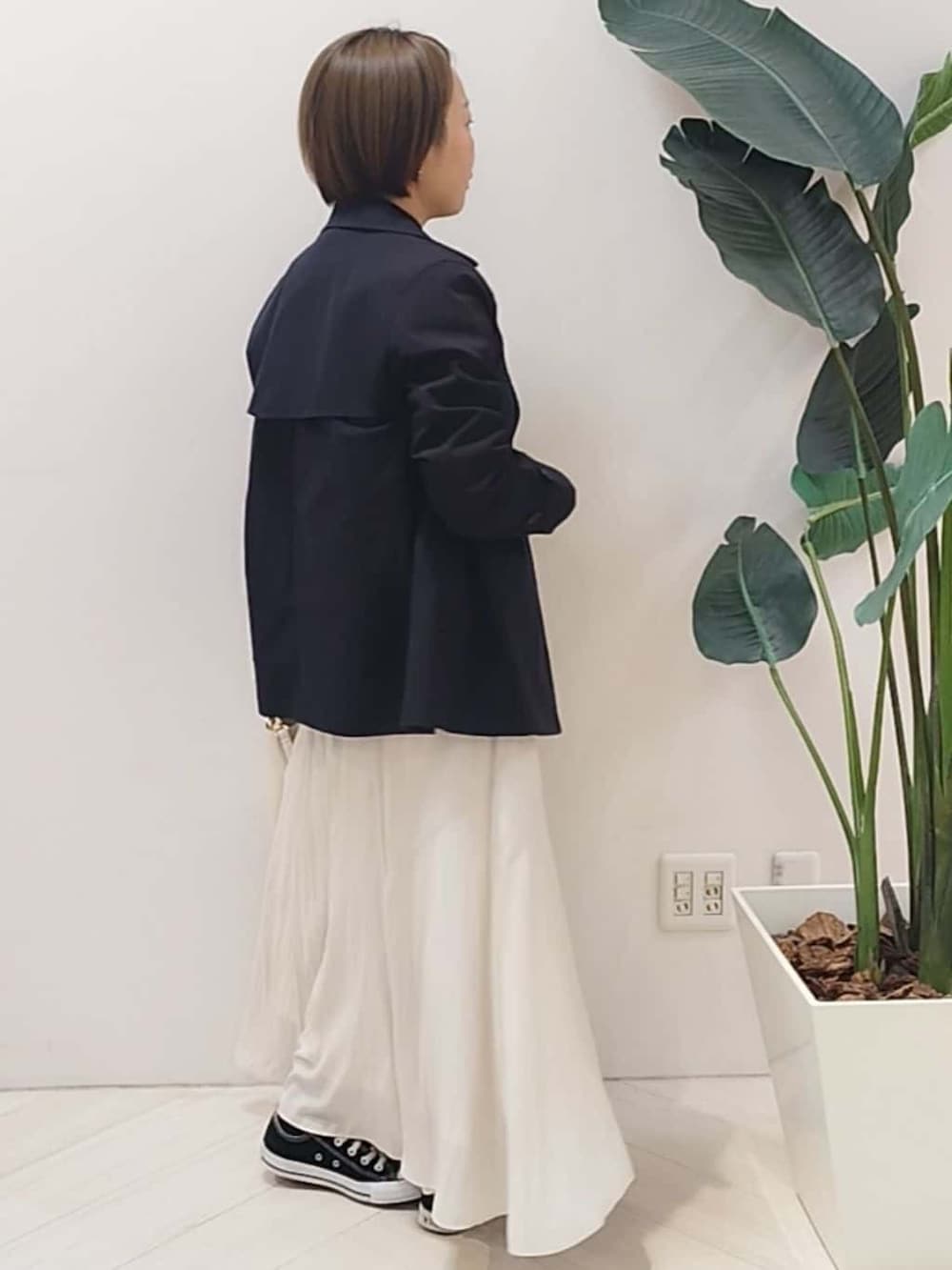 ブルー系のトレンチコート、ブラック系のニット/セーター、ベージュ系のスカートを着用したレディースの春コーディネートの6枚目の写真