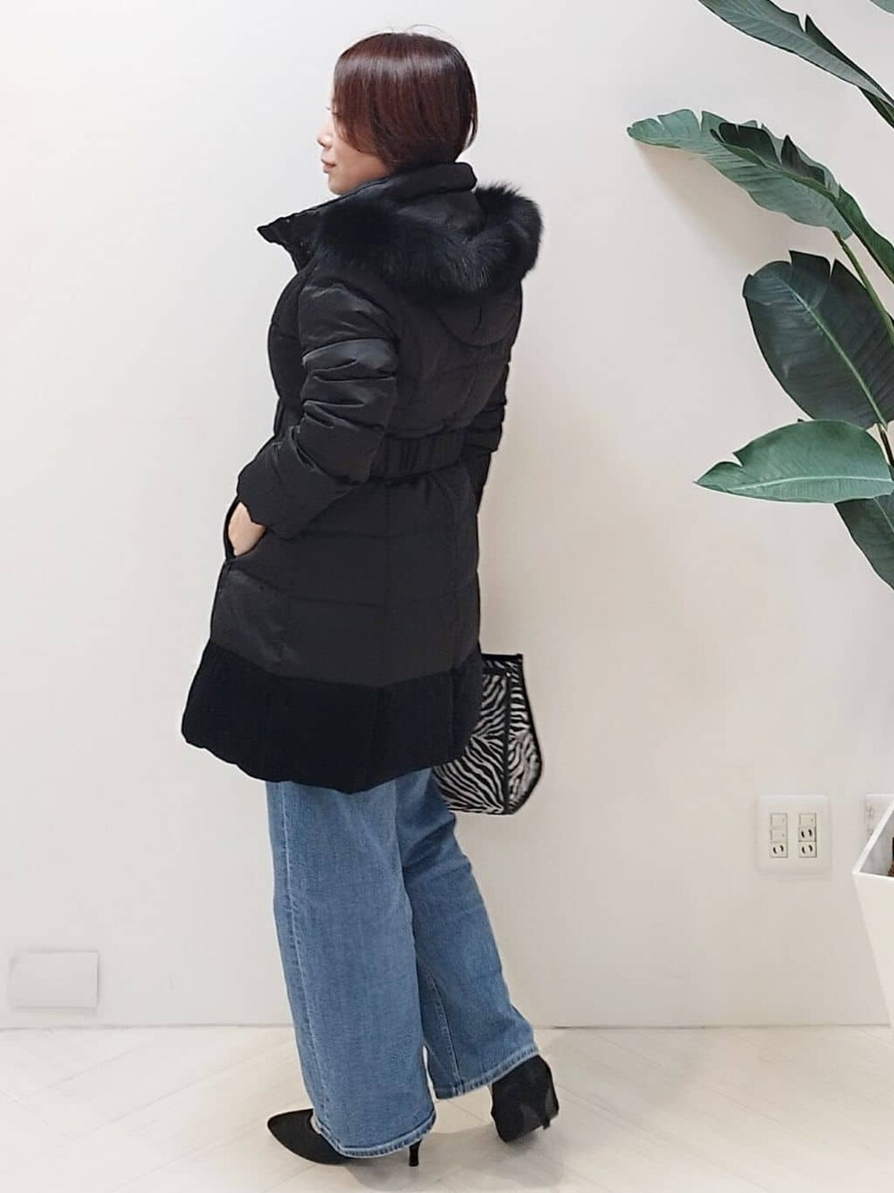 ブラック系のダウンジャケット/コート、ブルー系のニット/セーター、ブルー系のデニムパンツを着用したレディースの冬コーディネートの5枚目の写真