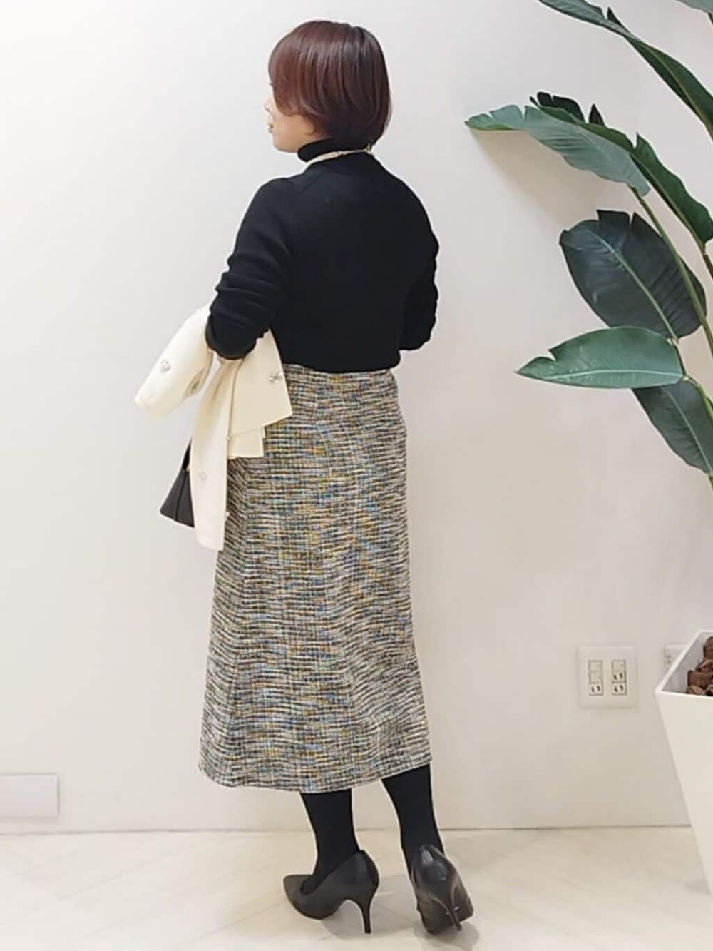 ブラック系のニット/セーター、ブラック系のスカート、ホワイト系のカーディガン/ボレロを着用したレディースの秋コーディネートの6枚目の写真