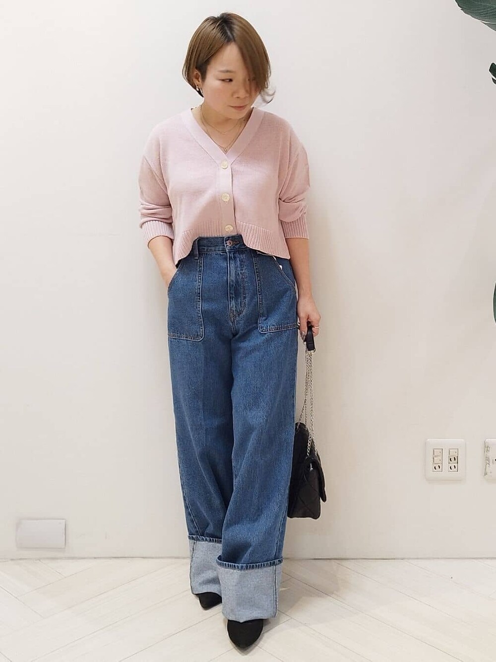 ピンク系のカーディガン/ボレロ、ブルー系のデニムパンツ、ブラック系のショルダーバッグを着用したレディースの冬コーディネートの2枚目の写真