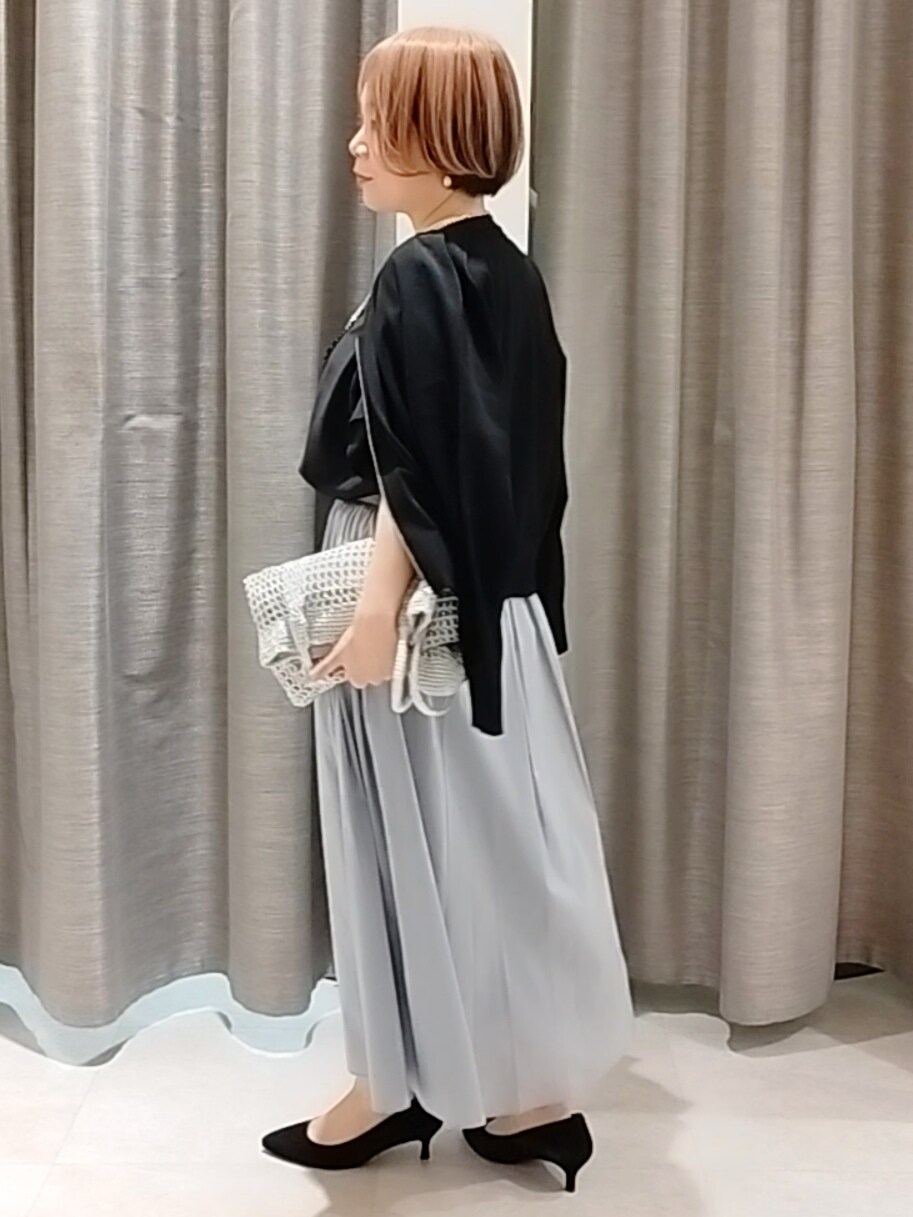 ブルー系のスカート、ブラック系のカーディガン/ボレロ、シルバー系のトートバッグを着用したレディースの春コーディネートの6枚目の写真