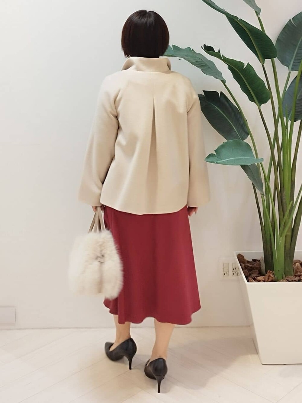 ベージュ系のその他アウター、ベージュ系のニット/セーター、レッド系のスカートを着用したレディースの冬コーディネートの7枚目の写真