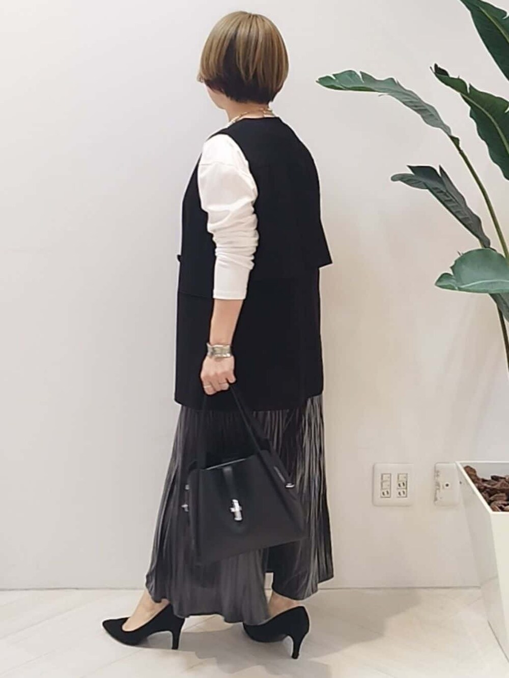 ブラック系のベスト、ホワイト系のTシャツ/カットソー、グレー系のスカートを着用したレディースの冬コーディネートの5枚目の写真