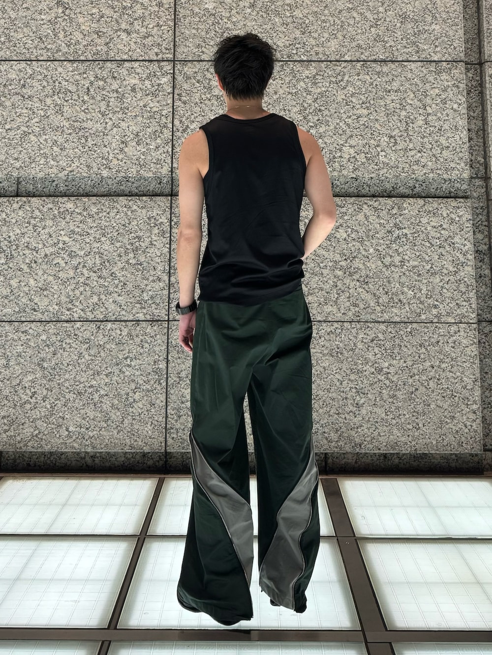 ブラック系のタンクトップ、グリーン系のパンツ、ブラック系のスニーカーを着用したメンズの夏コーディネートの2枚目の写真