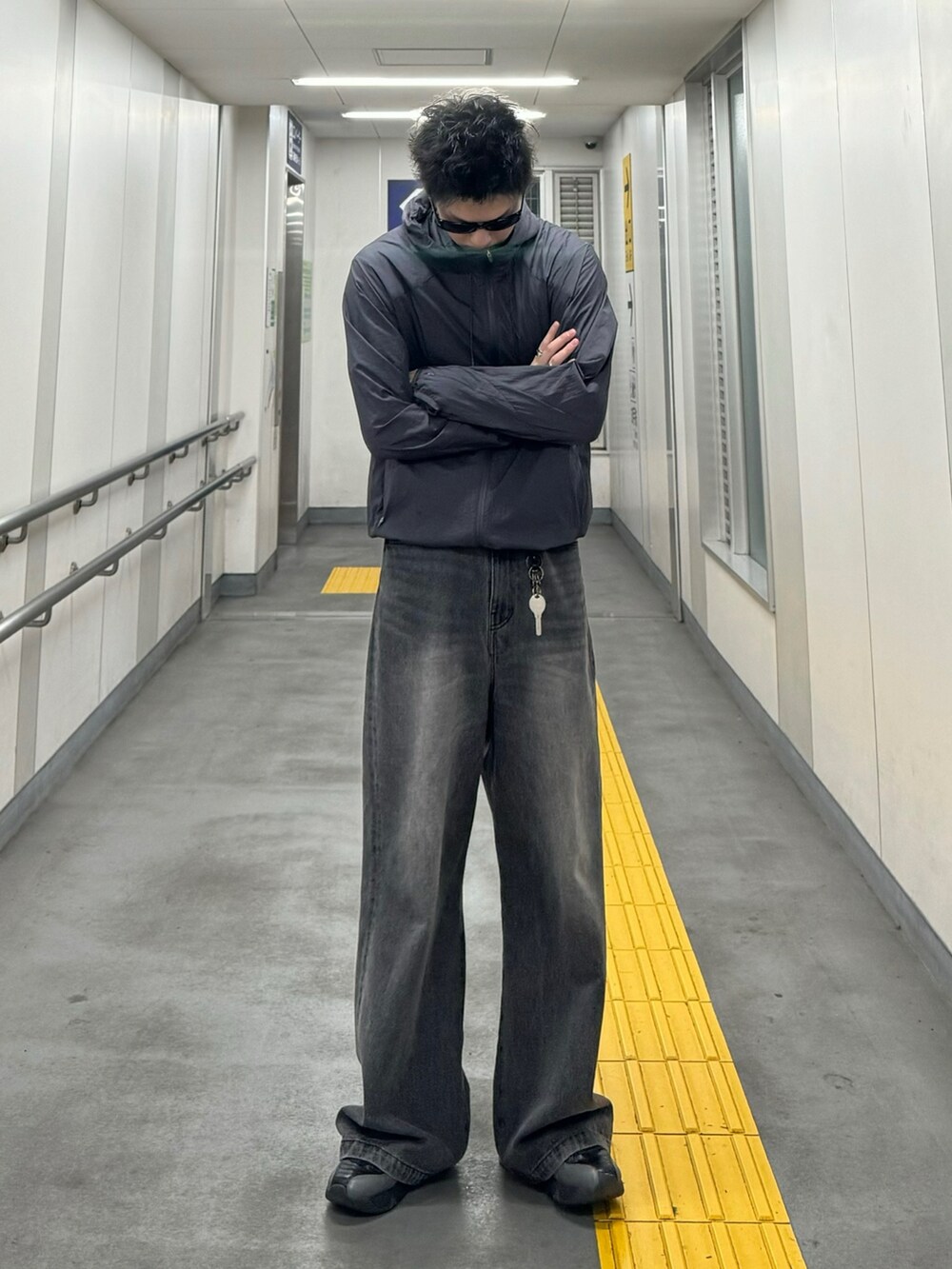 パープル系のマウンテンパーカー、ブラック系のデニムパンツ、ブラック系のスニーカーを着用したメンズの夏コーディネートの2枚目の写真