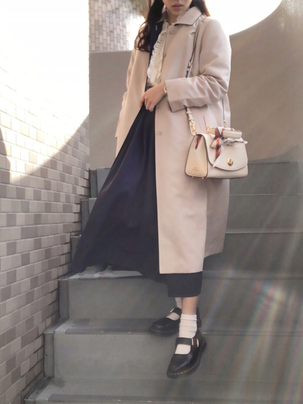 ブラック系のブーツ、ホワイト系のショルダーバッグ、ホワイト系のイヤーカフを着用したレディースの冬コーディネートの2枚目の写真