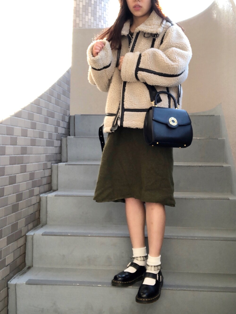 ブラック系のブーツ、ホワイト系のジャケット/アウターを着用したレディースの冬コーディネートの2枚目の写真