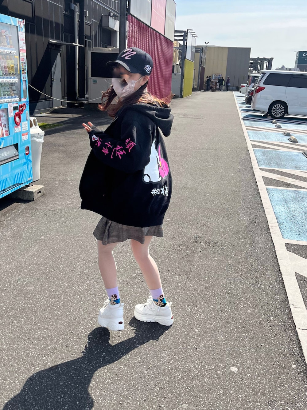 ブラック系のパーカー、ブラウン系のスカート、ホワイト系のスニーカーを着用したレディースの冬コーディネートの3枚目の写真