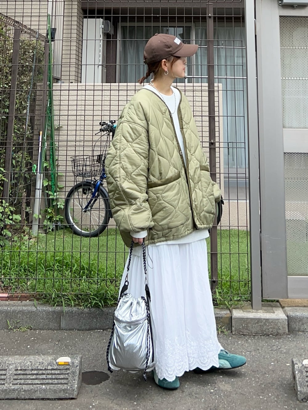 ホワイト系のスカート、シルバー系のトートバッグ、グリーン系のスニーカーを着用したレディースの秋コーディネートの3枚目の写真