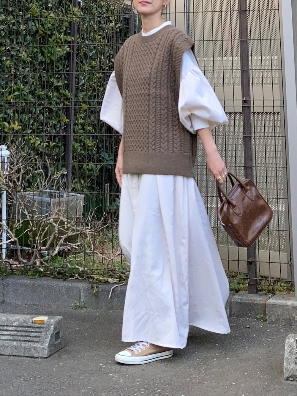 ブラウン系のベスト、ベージュ系のワンピース、ブラウン系のショルダーバッグを着用したレディースの冬コーディネートの3枚目の写真