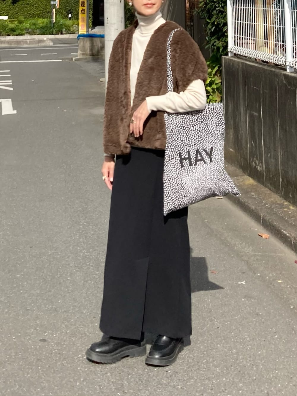 グリーン系のベスト、ブラック系のスカート、ブラック系のブーツを着用したレディースの秋コーディネートの2枚目の写真