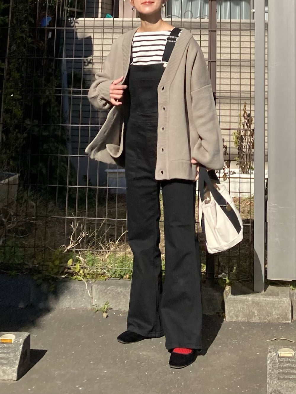 ベージュ系のカーディガン/ボレロ、ブラック系のサロペット/オーバーオール、ホワイト系のトートバッグを着用したレディースの冬コーディネートの4枚目の写真