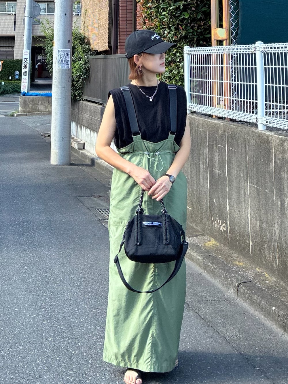 ブラック系のTシャツ/カットソー、グリーン系のジャンパースカート、ブラック系のトートバッグを着用したレディースの夏コーディネートの3枚目の写真