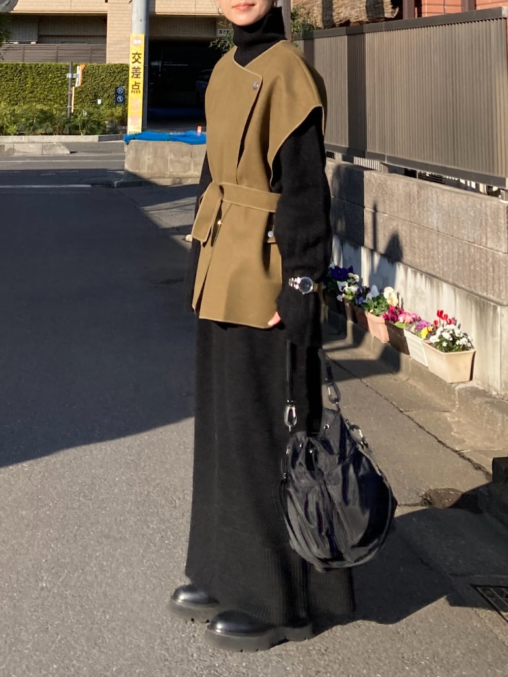 グリーン系のベスト、ブラック系のワンピース、ブラック系のショルダーバッグを着用したレディースの冬コーディネートの3枚目の写真