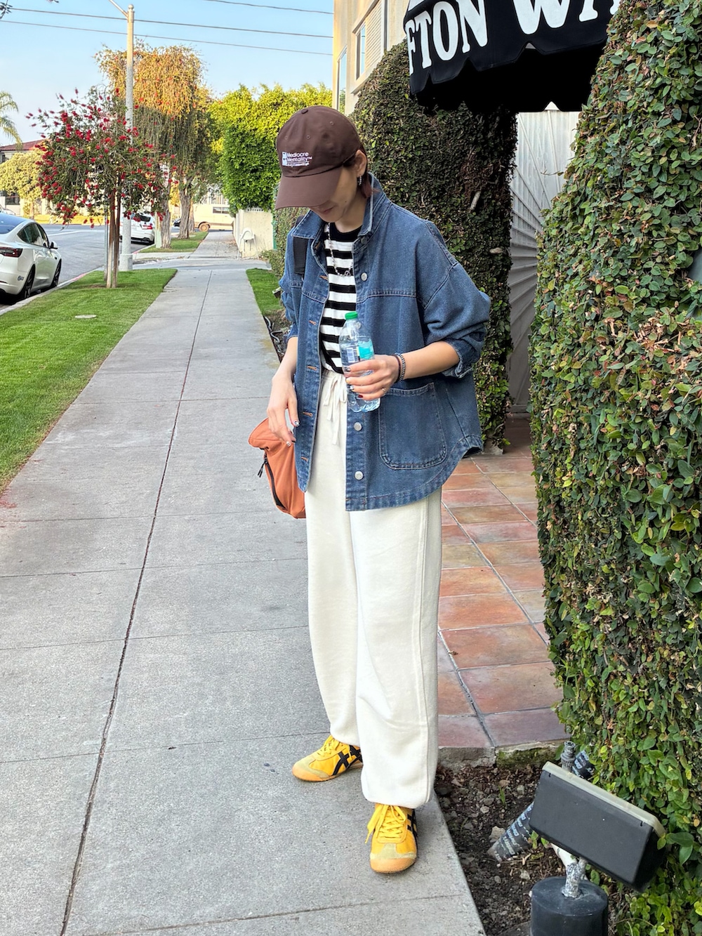 ブラック系のTシャツ/カットソー、オレンジ系のショルダーバッグ、ブルー系のデニムジャケットを着用したレディースの春コーディネートの4枚目の写真