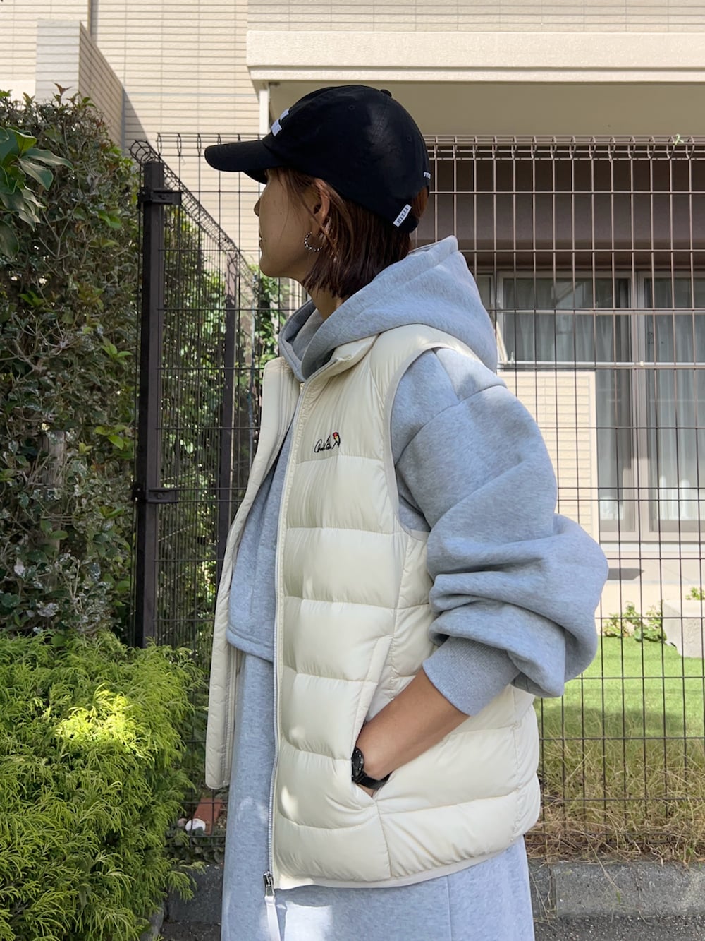 グレー系のワンピース、ブラック系のトートバッグ、ホワイト系のダウンベストを着用したレディースの秋コーディネートの4枚目の写真