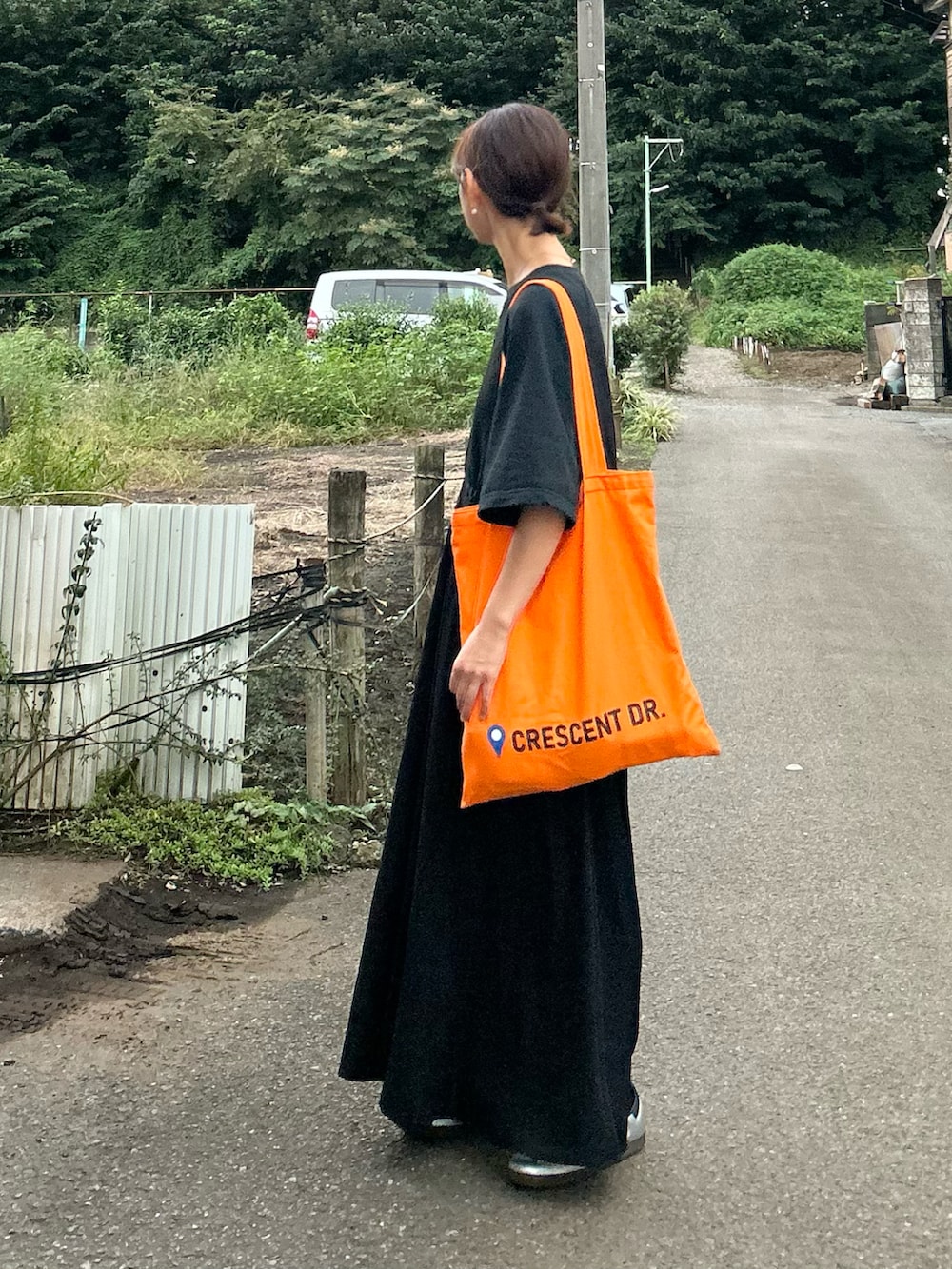 ブラック系のワンピース、オレンジ系のトートバッグ、シルバー系のスニーカーを着用したレディースの秋コーディネートの5枚目の写真