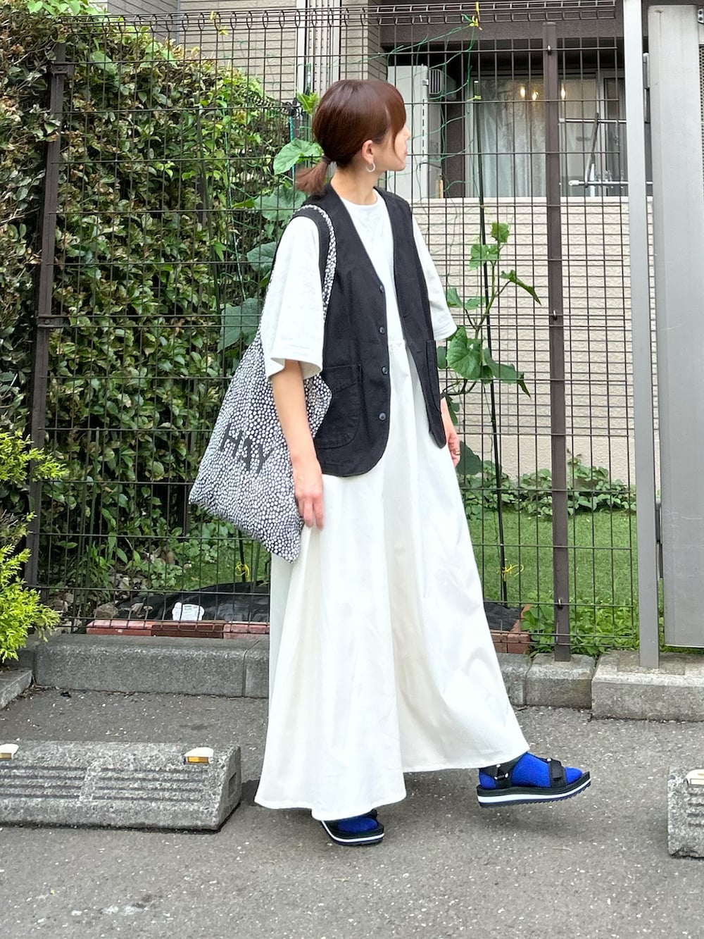 ベージュ系のワンピース、ブラック系のベスト、ブラック系のサンダルを着用したレディースの夏コーディネートの2枚目の写真