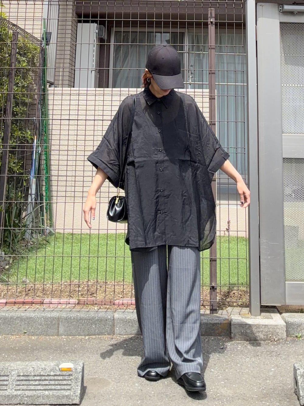 ブラック系のシャツ/ブラウス、グレー系のスラックス、ブラック系の財布を着用したレディースの春コーディネートの3枚目の写真