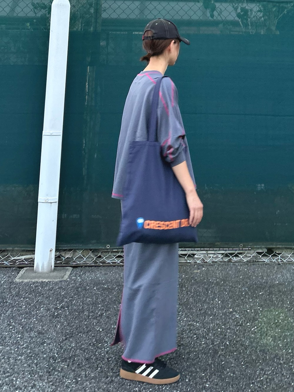 グレー系のTシャツ/カットソー、グレー系のスカート、ブルー系のトートバッグを着用したレディースの秋コーディネートの5枚目の写真