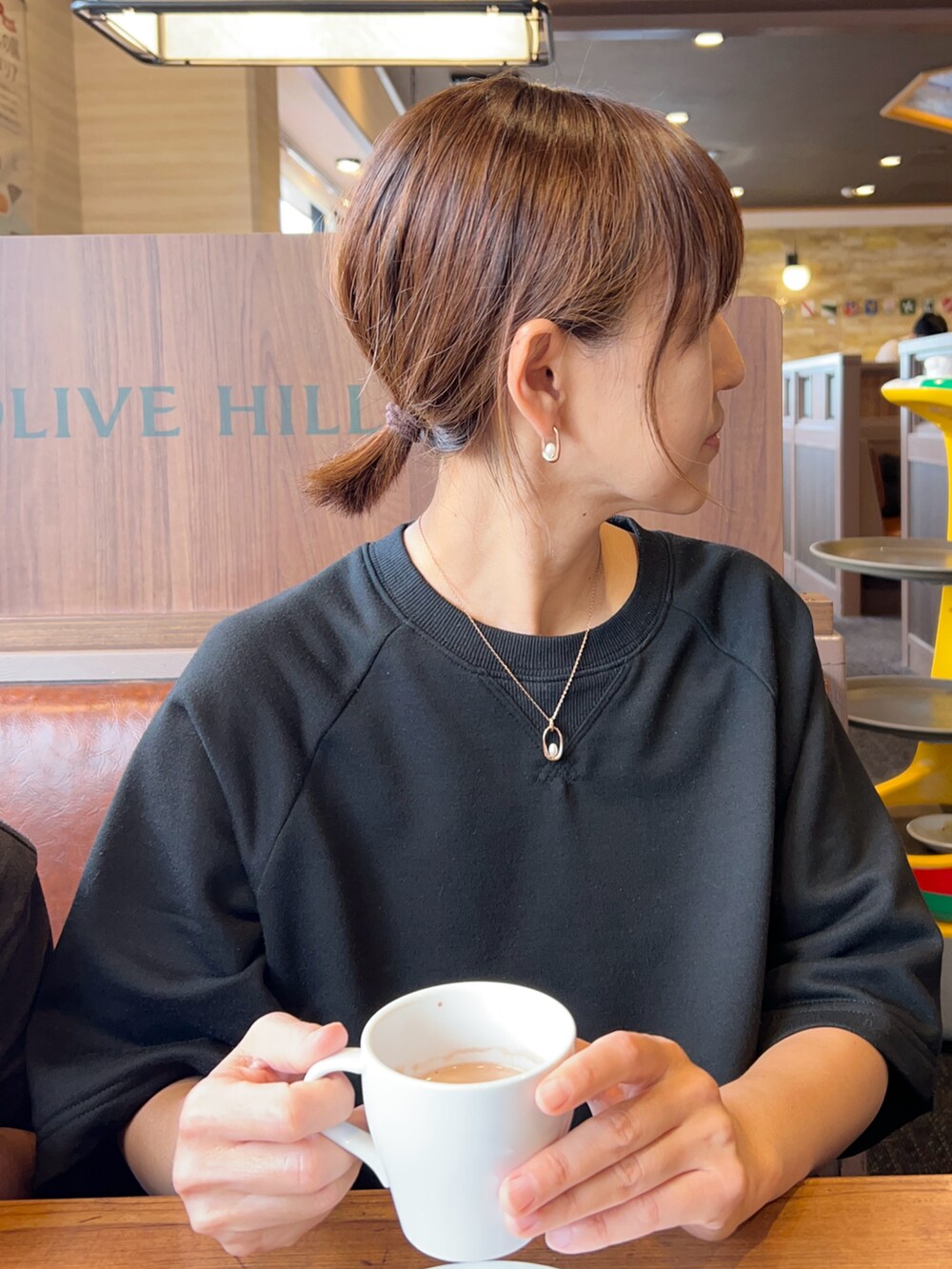 ブラック系のワンピース、オレンジ系のトートバッグ、シルバー系のスニーカーを着用したレディースの秋コーディネートの2枚目の写真