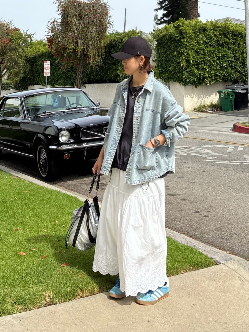 ブルー系のデニムジャケット、シルバー系のトートバッグ、ホワイト系のスカートを着用したレディースの春コーディネートの5枚目の写真