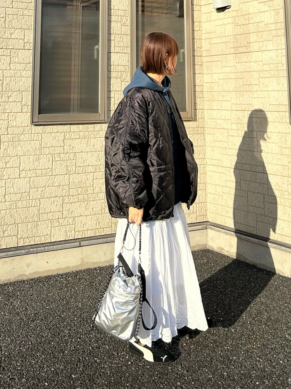 ブラック系のブルゾン、ブルー系のパーカー、シルバー系のトートバッグを着用したレディースの冬コーディネートの3枚目の写真