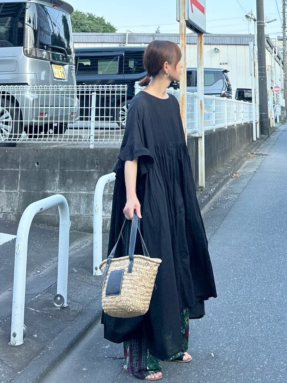 ブラック系のワンピース、ブラック系のかごバッグ、ブラック系のサンダルを着用したレディースの夏コーディネートの2枚目の写真