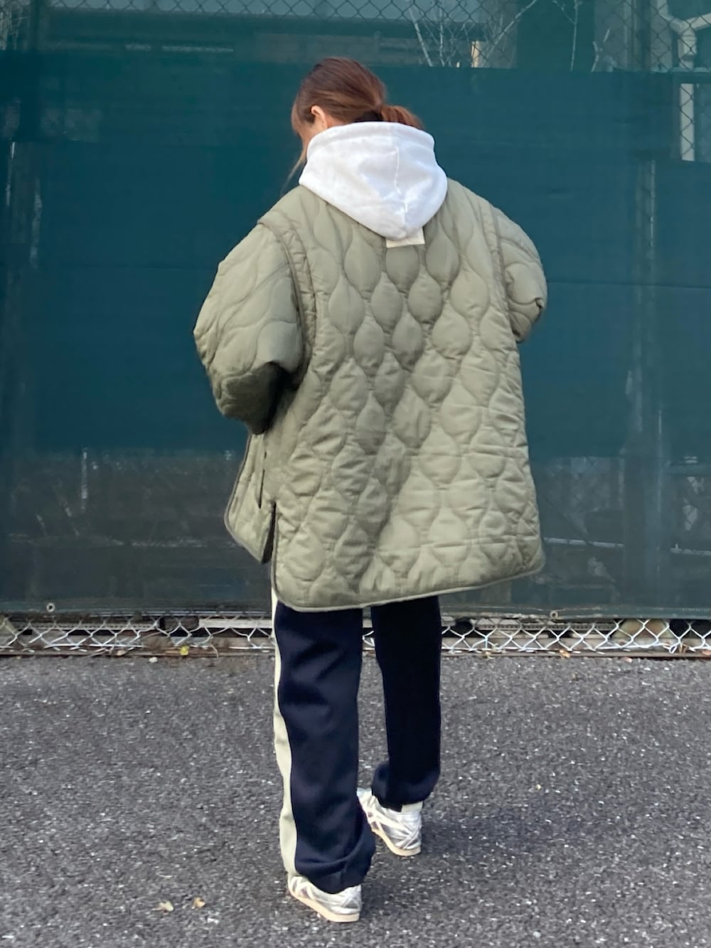 グリーン系のブルゾン、グレー系のパーカー、ブルー系のスウェットパンツを着用したレディースの冬コーディネートの3枚目の写真