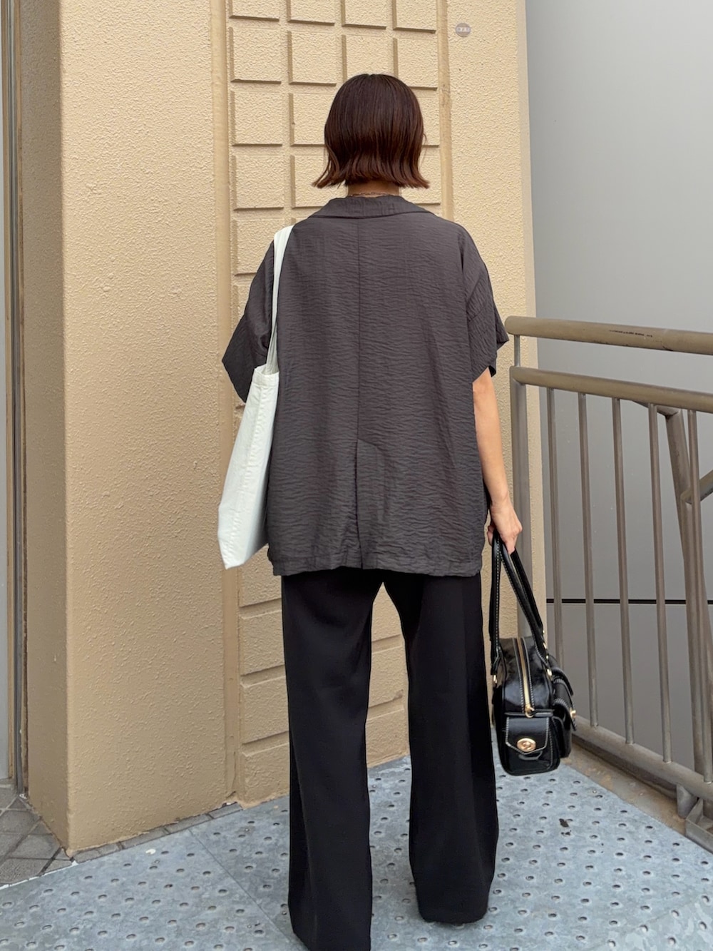 ホワイト系のTシャツ/カットソー、グレー系のテーラードジャケット、ブラック系のスラックスを着用したレディースの夏コーディネートの4枚目の写真